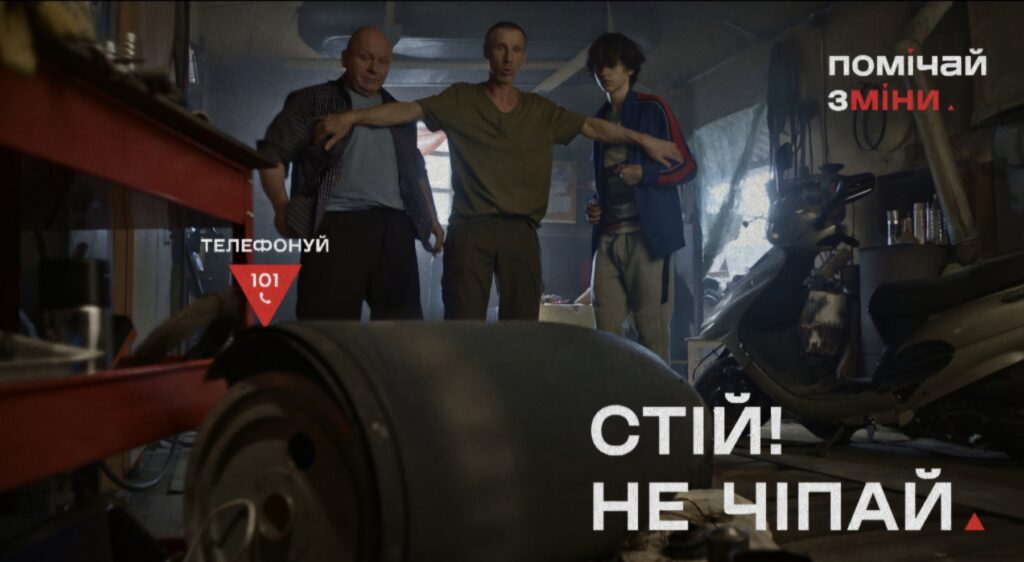 Соціальний постер українською мовою: троє людей у приміщенні, один із них простягає руки, ніби зупиняючи інших; на передньому плані — великий циліндричний предмет; праворуч — скутер та інструменти; текст — “ТЕЛЕФОНУЙ 101”, “СТІЙ! НЕ ЧІПАЙ”, “ПОМІЧАЙ ЗМІНИ”