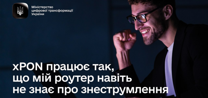 Людина в окулярах і темній куртці сидить перед комп’ютером, піднявши кулак у жесті задоволення. Угорі ліворуч логотип Міністерства цифрової трансформації України.