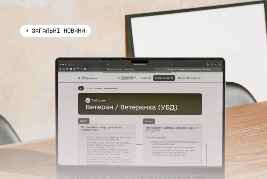 Ноутбук на дерев’яному столі з відкритою сторінкою урядового сайту України, розділ для ветеранів. На екрані видно інструкції щодо отримання статусу учасника бойових дій та перевірки підстав для звільнення зі служби
