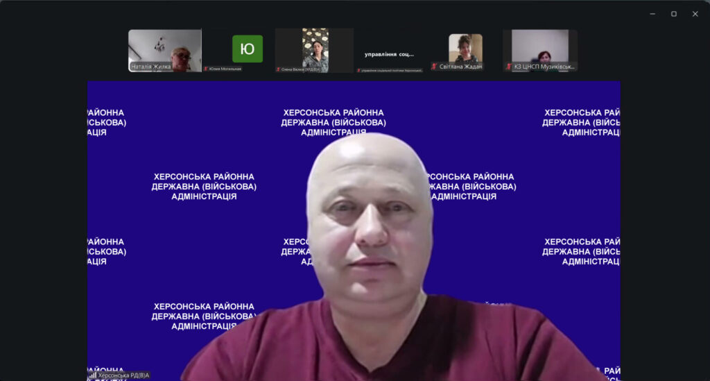 Скріншот відеоконференції. У центрі — учасник на синьому фоні з білим написом «Херсонська районна державна (військова) адміністрація». Угорі — маленькі вікна з іншими учасниками.