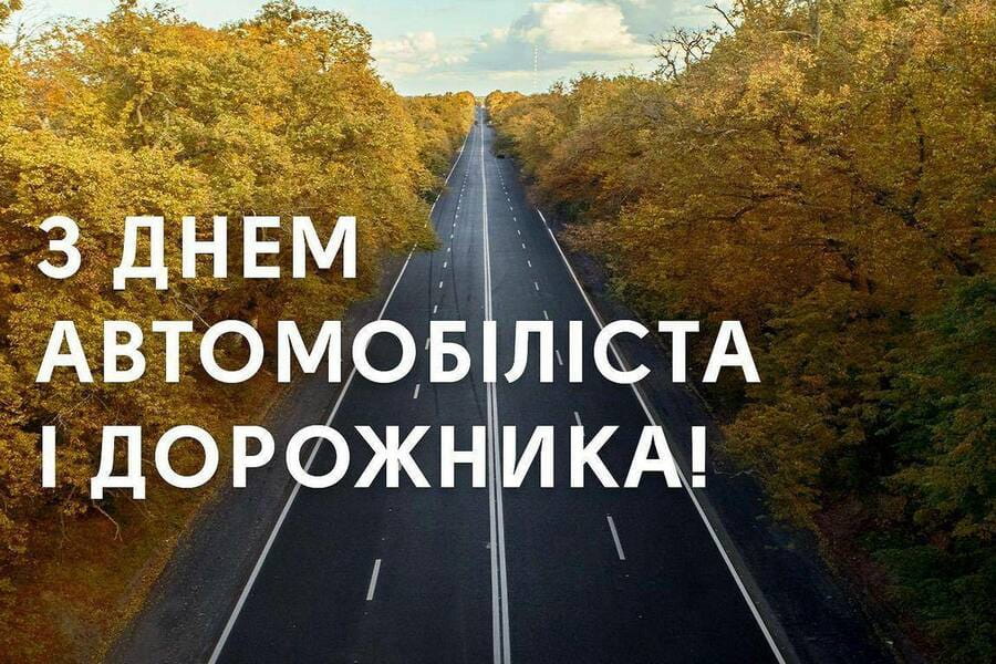 Порожня пряма дорога серед осінніх дерев із жовтим та помаранчевим листям. Угорі напис українською мовою: «З Днем автомобіліста і дорожника!»