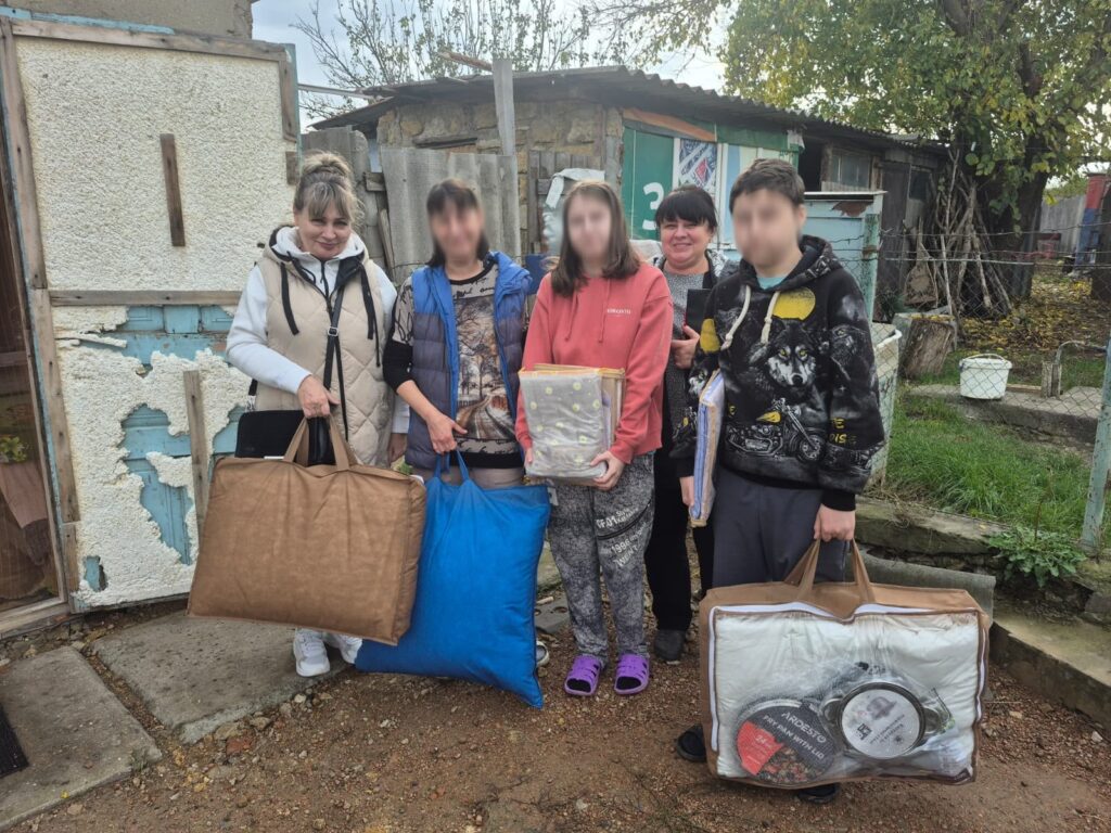 Люди біля будинку передають родині подушки, ковдри та речі домашнього вжитку як допомогу.